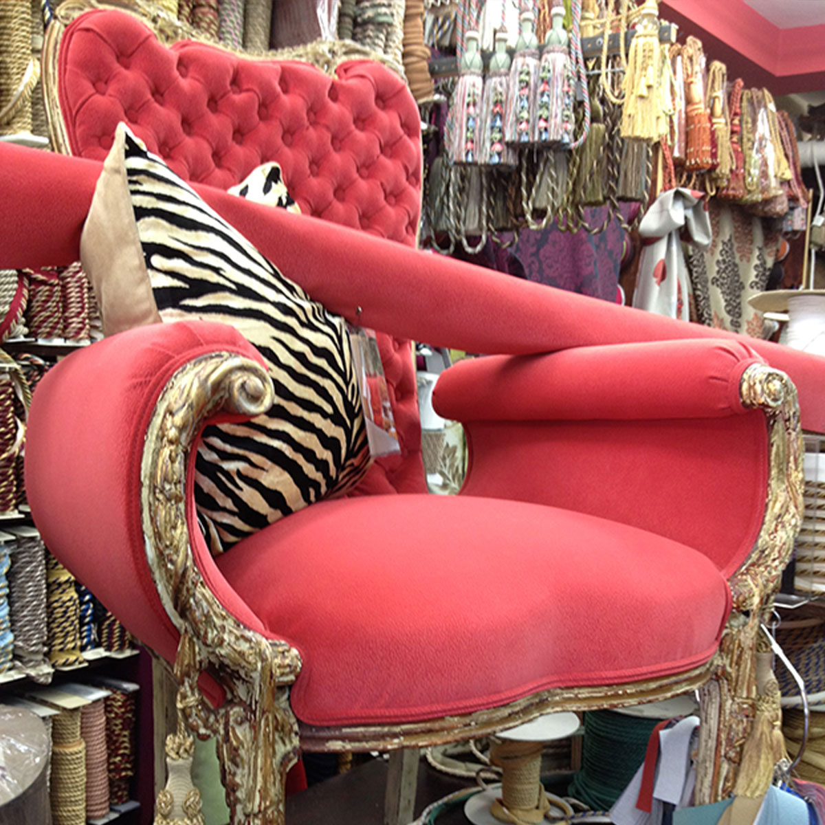 Coral upholstered armchair with carved frame and zebra-print pillow