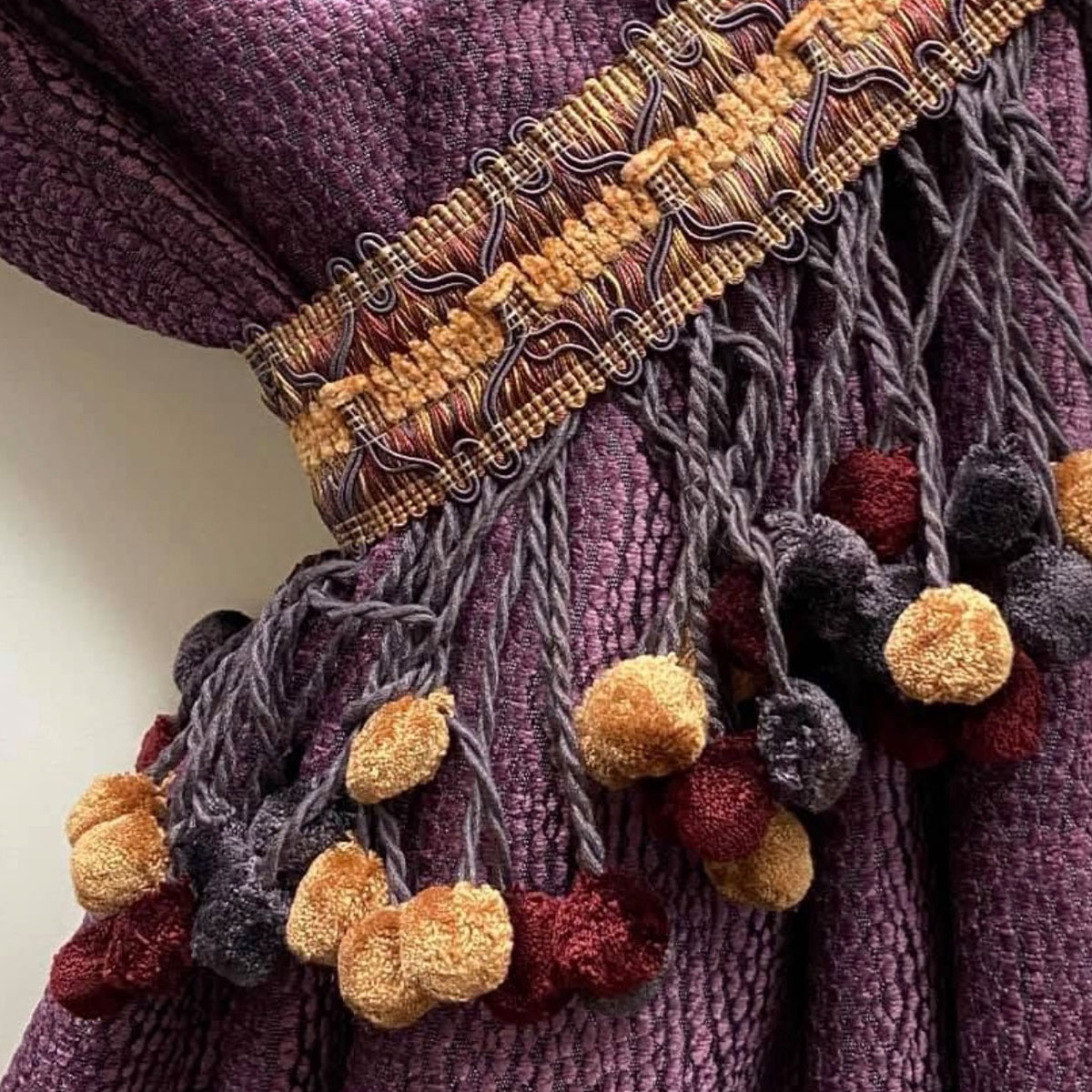 Plum drapery fabric with decorative fringe and tassel trim